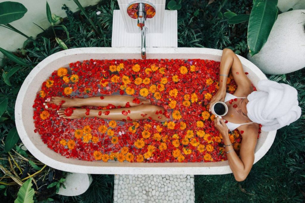 Woman enjoying a flower bath with coffee in a tropical Bali garden
