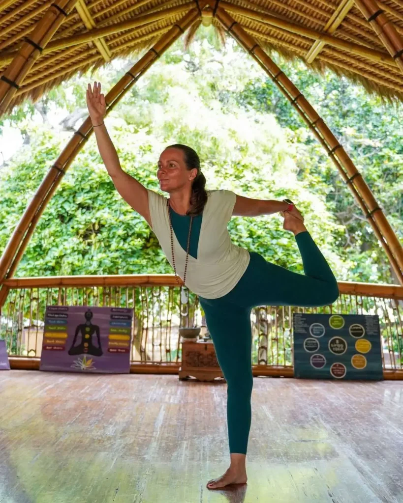 Yoga teacher practicing Dancer Pose in a bamboo yoga shala in Sanur, Bali.